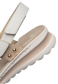 White and beige sandal with textured thick sole, suede and leather straps, and gold-tone studs on the side.