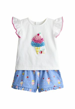 Camiseta blanca para niño pequeño con diseño de helado en rosa y azul y mangas con volantes, combinada con pantalones cortos azules decorados con estampados de helado y frutas.