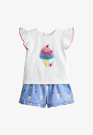Camiseta blanca para niño pequeño con diseño de helado en rosa y azul y mangas con volantes, combinada con pantalones cortos azules decorados con estampados de helado y frutas.