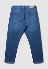 Un jean en denim bleu posé à plat, montrant le dos avec deux poches, des passants de ceinture et une étiquette en cuir marron sur la ceinture.