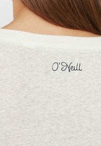 Weißer, strukturierter Stoff mit einem feinen Muster; zeigt ein schwarzes, geschwungenes Logo mit der Aufschrift "O'Neill" am hinteren Kragen.