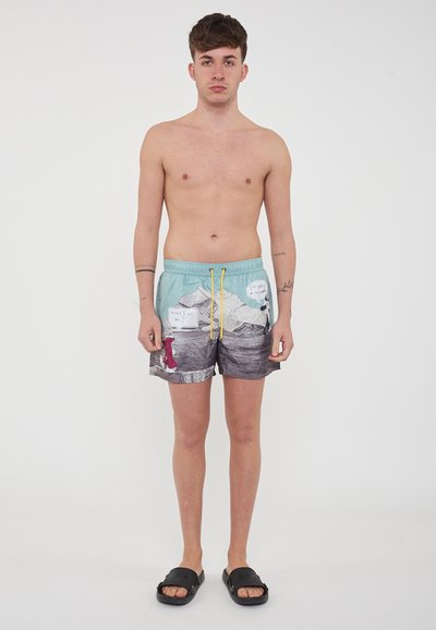 Costumi da bagno leggeri blu chiaro e grigi con grafiche di montagne e fumetti. Presentano un elastico in vita con lacci gialli. Design con fronte piatto.