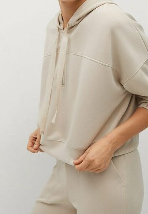 Beige Kapuzenpullover mit Kordelzug, weichem Stoff, lockerer Passform und einem horizontalen Nahtdetail über der Brust. Glatte Textur, minimalistisches Design.