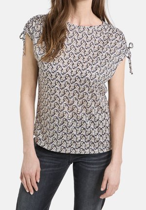 Korte mouwen top met een bloemenpatroon in beige en bruin. Heeft strikdetails op de schouders en een ontspannen pasvorm. Gemaakt van lichtgewicht stof.