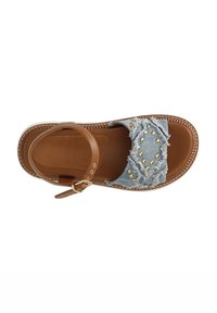 Denim sandal with brown leather strap and buckle. Distressed denim upper adorned with gold studs. Flat sole with woven detailing.