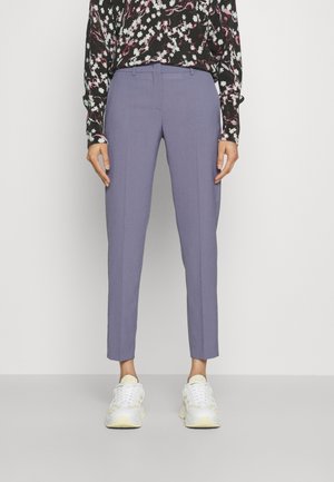 Pantaloni su misura di un leggero viola con una vestibilità dritta, orlo a risvolto e linee di piega sottili. Abbinati a sneakers bianche e gialle.