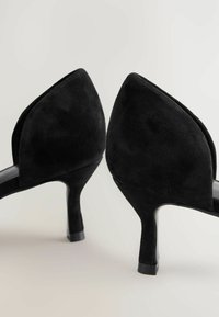 Chaussures à talons hauts en suède noir avec un design à dos pointu et un talon fin, dotées d'un intérieur lisse en noir.