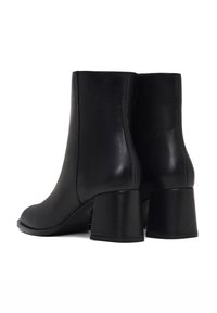 Bottines noires en cuir avec une texture lisse, des orteils arrondis et des talons carrés. Design simple sans matériel ou motifs visibles.