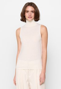 Hihaton, vaalean kerma turtleneck-toppi, joka on valmistettu pehmeästä neulekankaasta. Siinä on mukautuva muotoilu ja hienovarainen rakenne, suora helma.