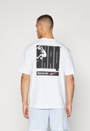 White cotton t-shirt featuring a large black graphic on the back with "SHAQ" text and a silhouette of a basketball player. Reebok logo underneath.
