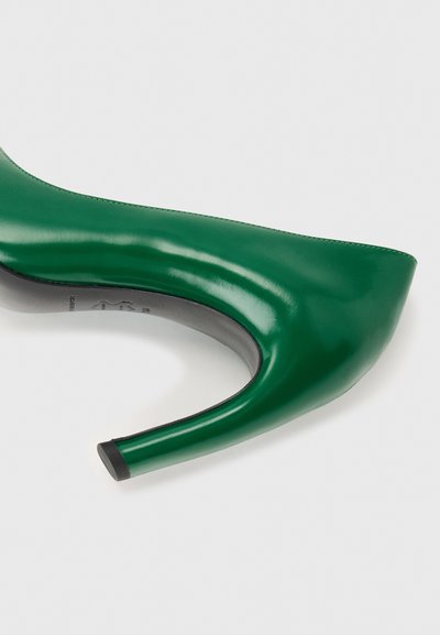 Πράσινο γυναικείο παπούτσι με ψηλό τακούνι, μυτερή μύτη και λεπτό τακούνι, εμφανίζεται από το πλάι σε ουδέτερο φόντο.