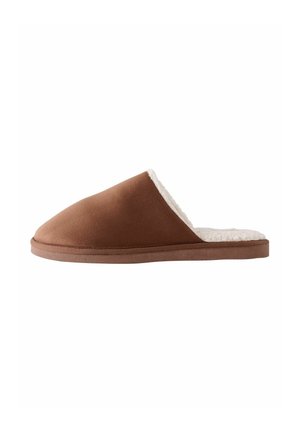 Chausson en suede marron avec une douce doublure en fausse fourrure blanche, présentant un design à bout fermé et une semelle plate et texturée.