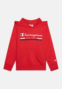 Sweat à capuche rouge Champion avec poche frontale, texte logo blanc et noir "Champion New York Depuis 1919," et petit logo sur la manche gauche.