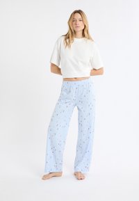 T-shirt blanc court et pantalon de pyjama bleu clair avec un motif floral, doté d'une taille élastique et d'une coupe ample.
