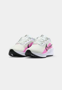 Baskets de sport blanches avec des accents roses, dessus en mesh respirant, semelles noires et détails réfléchissants. Conçues pour le confort et la performance.