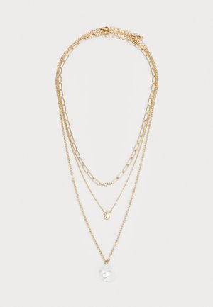 Colar de ouro com três camadas e diferentes estilos de correntes, apresentando uma pequena gema transparente, um encanto abstrato em ouro e um grande pingente de pérola branca.