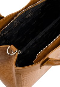 Sac �à main en cuir marron texturé avec une fermeture éclair ouverte montrant un intérieur en tissu noir avec la marque "Venezia" et plusieurs compartiments.