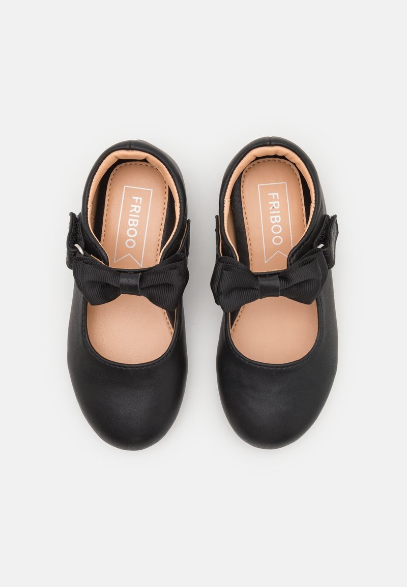 Paire de chaussures noires pour tout-petits avec bouts ronds, nœuds décoratifs et brides à la cheville, étiquetées "FRIBOO" à l'intérieur.