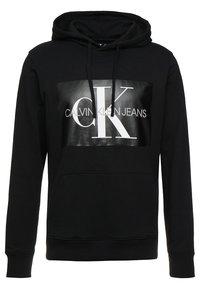 Felpa nera con cappuccio realizzata in tessuto morbido, caratterizzata da un grande pannello grafico lucido con il logo "CK" bianco e il testo "CALVIN KLEIN JEANS" al centro.