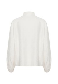 Hvid tekstureret skjorte med høj hals, brede ærmer og samlede manchetter. Stoffet har et subtilt, bølget mønster i hele skjorten.