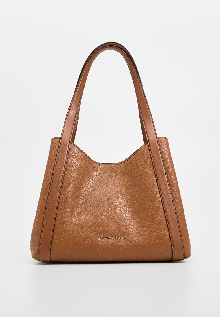 Bruine leren schoudertas met gestructureerde afwerking, twee stevige handvatten en een subtiele logosticker aan de voorkant. Ruimtelijk, taps toelopend ontwerp.