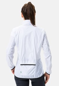 Weißer Windbreaker mit hohem Kragen, langen Ärmeln und schwarzen Akzenten. Verfügt über eine Rückentasche und eine leichte, glatte Textur.