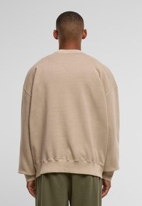 Beige oversized sweatshirt med rund halsudskæring, ribbede manchetter og kant. Glat tekstur og dropped shoulders. Casual, afslappet pasform.