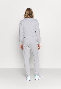 Világosszürke pulóver és melegítőnadrág szett, bordázott mandzsettákkal és derékpánttal, puha tapintással és egyszerű, laza dizájnnal.