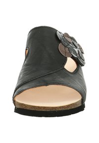 Zwarte leren sandaal met een gebogen ontwerp en uitsparingen, met een gelaagde bloemaccent in bruin en grijs, en een lichtkleurige zool.