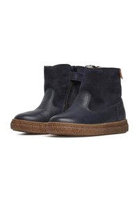 Námořnické kožené kotníkové boty s texturovanou hnědou podrážkou, se zipem po straně a měkkými semišovými akcenty pro zvýraznění detailu a kontrastu.