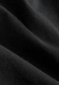 Tela de algodón negra con una textura suave. La superficie presenta un fino patrón acanalado, que destaca su caída blanda y flexible.