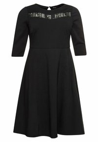 Robe noire à manches trois quarts, dotée d'un panneau en dentelle transparente au niveau de la poitrine, d'une taille cintrée et d'une jupe évasée. Texture de tissu lisse.