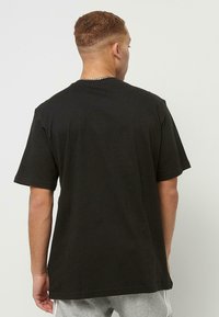 Zwarte katoenen t-shirt met een ronde hals, korte mouwen en een losse pasvorm. Heeft een simpele achterkant zonder extra patronen of details.