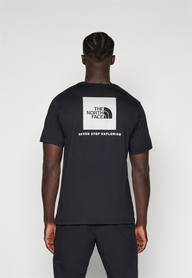 Crna pamučna majica s kratkim rukavima, s kvadratnom grafikom na kojoj se nalaze "THE NORTH FACE" logo i natpis "NEVER STOP EXPLORING" na leđima.