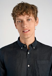 Camicia button-up blu scuro in lino, con tasca sul petto sinistro, colletto strutturato e bottoni bianchi sul davanti.