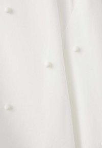 Tissu blanc avec une texture légère et transparente comportant de petits points en relief espacés régulièrement.