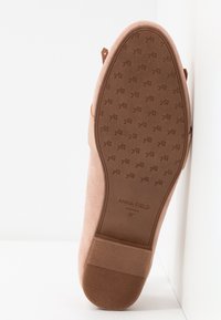 Semelle de chaussure en daim rose avec un grip à motif, logo en relief et marquage de taille 37. La vue de côté montre un design effilé et des détails d'usure légère.