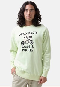 Sudadera verde clara con estampado gráfico que presenta una motocicleta y texto. Puños y dobladillo acanalados, confeccionada en tela suave, ajuste relajado.