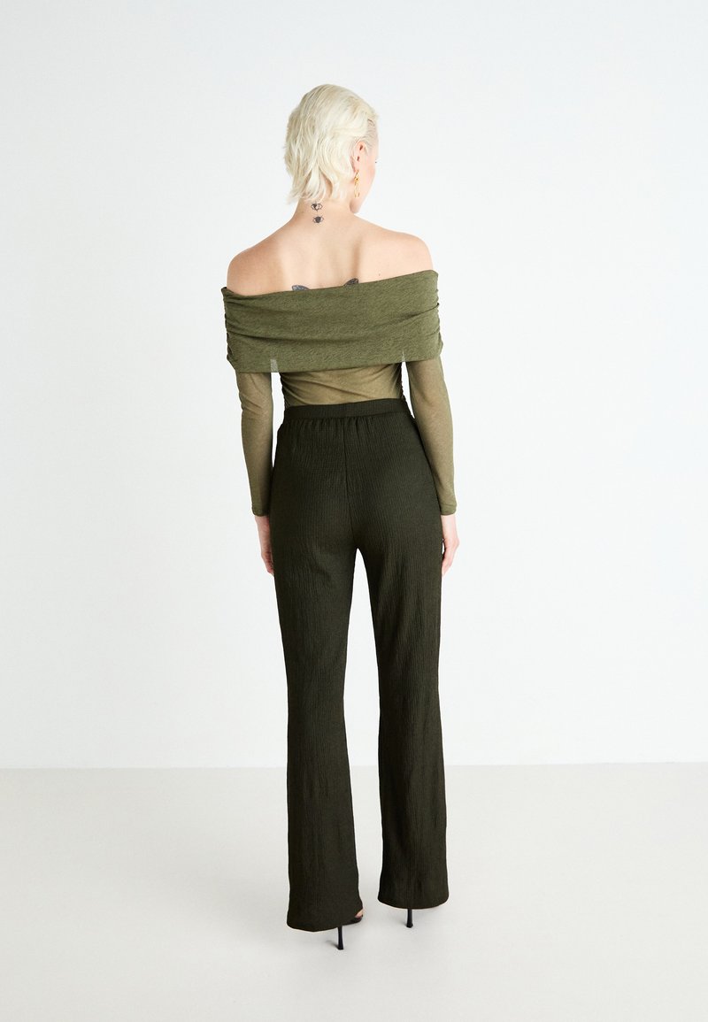 Olivegrünes Off-Shoulder-Oberteil mit gerafftem Design und langen Ärmeln, kombiniert mit passenden strukturierten weit geschnittenen Hosen.