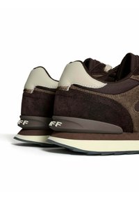 Pair of brown and beige suede sneakers with chunky soles, viewed from the back and slightly angled on a white background.