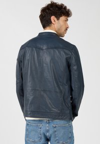 Navy Lederjacke mit glatter Textur, klassischem Design, taillierter Passform und einem dezenten Nahtmuster.