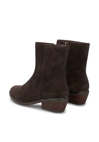 Botines de ante marrón oscuro con punta redonda, cierre de cremallera y tacón bajo apilado, que presentan un acabado liso alrededor de la base.