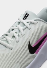 Αθλητικό παπούτσι ανοιχτού πράσινου χρώματος με υφή στην επάνω επιφάνεια, μαύρο λογότυπο swoosh, λευκά κορδόνια και μωβ λεπτομέρειες στη σόλα.