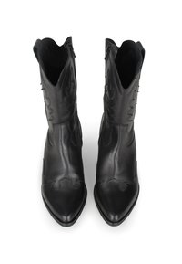 Botas de tobillo de cuero negro con puntas afiladas y costuras decorativas, que presentan un diseño curvado a lo largo de los lados y cremalleras internas.
