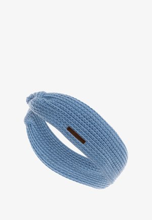 Dzianinowa opaska na głowę w jasnoniebieskim kolorze z teksturowanym wzorem. Posiada skręcony design i małą brązową metkę zamocowaną z boku.