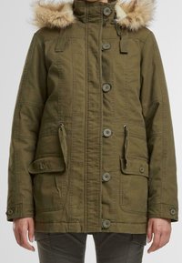 Olivově zelená parka bunda s kapuc�í lemovanou umělým kožíškem, zapínáním na druky a knoflíky, dvěma předními kapsami, nastavitelným pasem a texturovanou látkou.