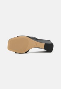 Sort hæl sandal med en glat overdel, åbent design og en tekstureret gummisål. Har en beige mellemsål med riller for bedre greb.