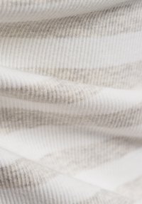 Textured fabric with vertical ribbing in muted beige and white stripes, displaying a soft, flexible, and slightly fuzzy appearance.