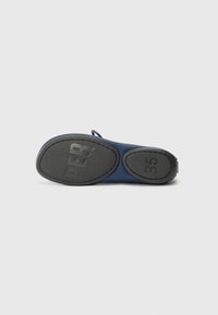 Semelle d'une chaussure bleu foncé avec une semelle en caoutchouc noire, montrant un texte en relief "PBR" et le numéro de taille "35" sur un fond uni.