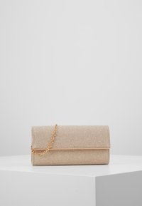 Béžová psaníčko s texturovaným povrchem, magnetickým uzávěrem a zlatým řetízkem. Obdélníkový tvar s elegantním designem.